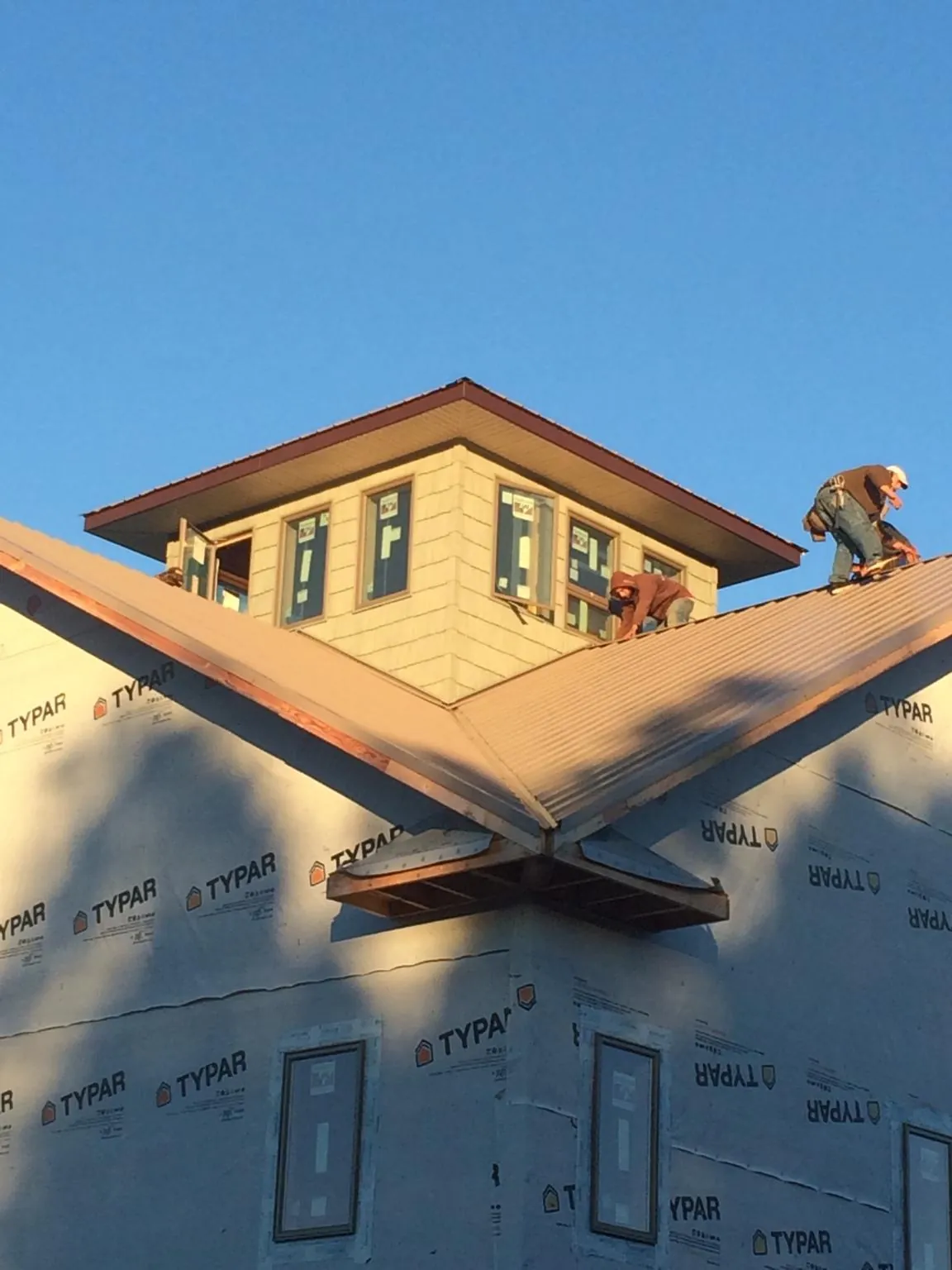 Roofers working around a rooftop cupola on a new metal roof at sunset — Roof Waterproofing in Modena by Roofing Brothers